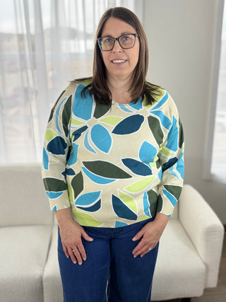 Woman wearing a colorful patterned sweater in a bright room.