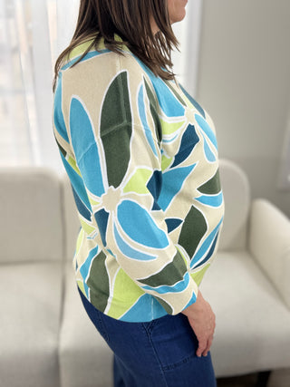 Person wearing a colorful floral-patterned shirt in a neutral setting