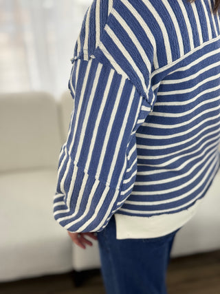 Person wearing a blue and white striped shirt with a blurred background
