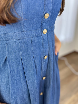 Close-up of a blue denim dress with gold buttons on a blurred background