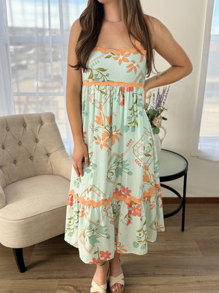 Woman wearing a floral dress in a room with a couch and table.