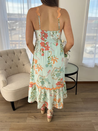 Woman wearing a floral dress in a room with a couch and table.