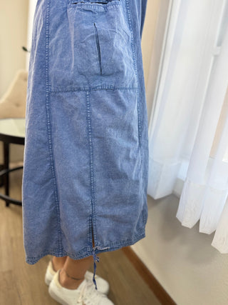 Blue denim skirt worn by a person indoors with white sneakers.