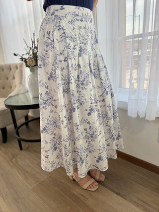 Person wearing a long floral skirt in a room with a couch and table.