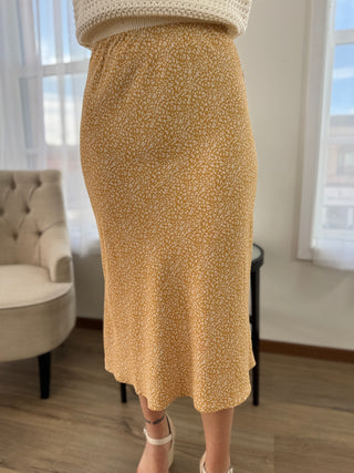 Person wearing a beige skirt in a room with a chair and window.