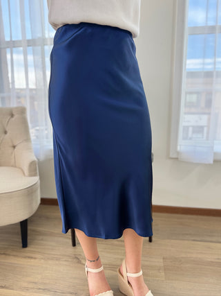 Person wearing a blue skirt in a room with a window and chair.