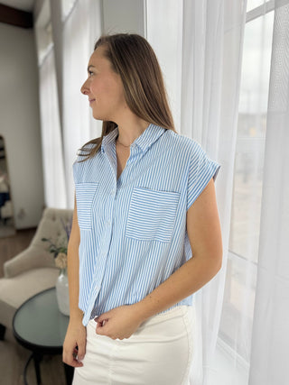 Woman wearing a blue and white striped shirt in a bright room with sheer curtains.