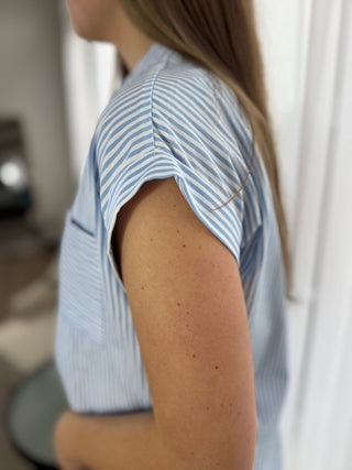 Person wearing a light blue and white striped shirt with a blurred background