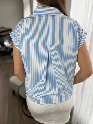 Person wearing a blue and white striped shirt in a room with curtains.