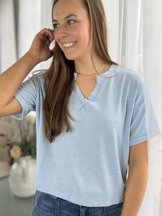 Woman wearing a light blue t-shirt indoors with a neutral background