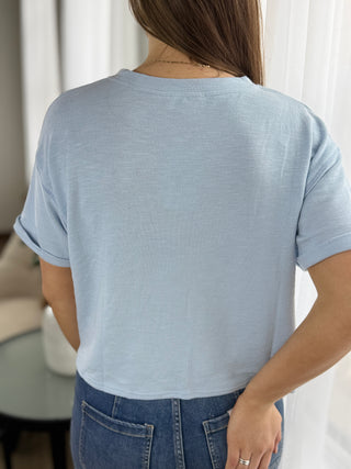 Person wearing a light blue t-shirt and jeans in a neutral setting