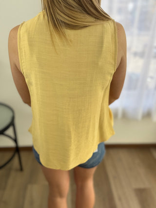 Person wearing a yellow sleeveless top and denim shorts in an indoor setting