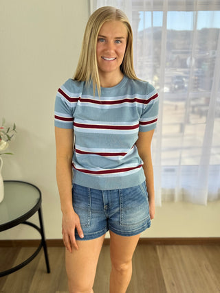 Woman wearing a striped sweater and denim shorts indoors.