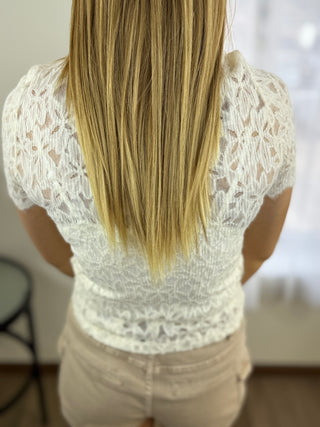 Person wearing a white lace top with a blurred background