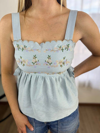 Light blue embroidered top worn by a person, with a blurred background
