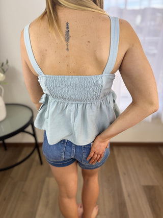 Person wearing a light blue top and denim shorts indoors.
