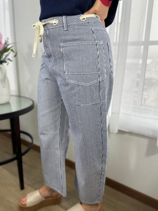Person wearing blue and white striped pants in a room with a table and window.