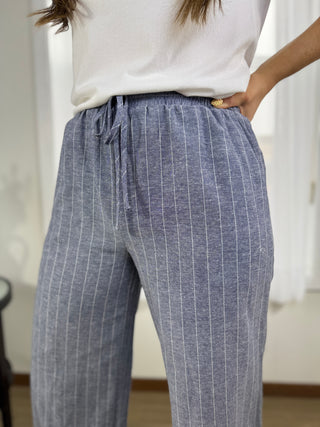 Person wearing blue striped pants with a white top in a blurred indoor setting
