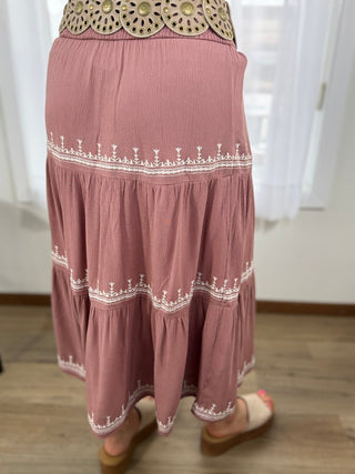 Pink skirt with white embroidery and gold waistband on a plain background