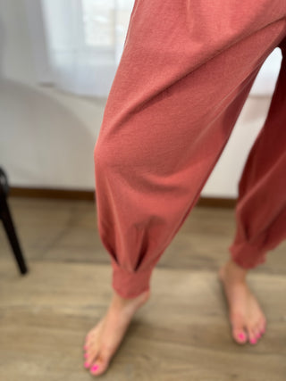 Person wearing pink pants standing on a wooden floor.