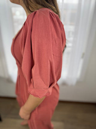 Person wearing a pink outfit with long sleeves in a softly blurred indoor setting