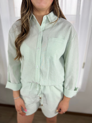 Person wearing a light green striped shirt and shorts indoors.