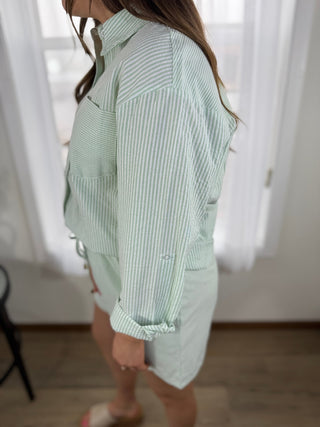 Person wearing a light green and white striped shirt with a matching skirt indoors.