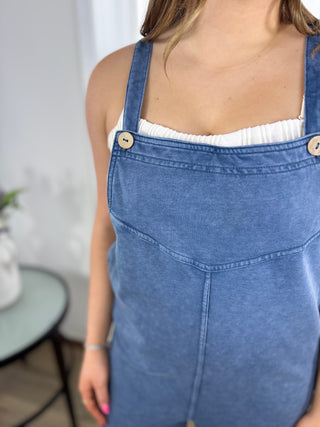 Person wearing a blue denim pinafore dress with a blurred background