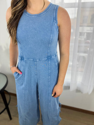 Person wearing a blue denim jumpsuit indoors with a blurred background