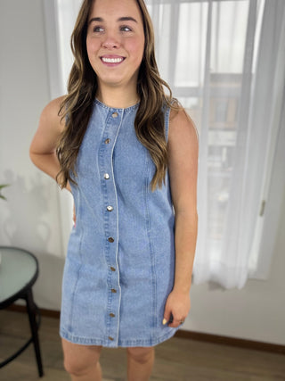 Woman wearing a denim dress indoors with a neutral background