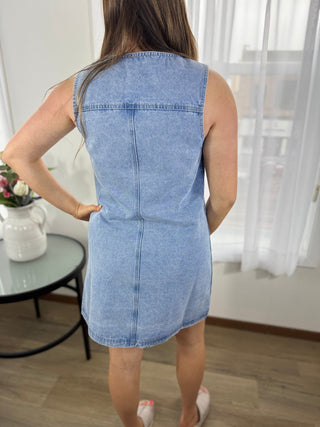 Woman wearing a blue denim dress in a room with white curtains and a glass table.