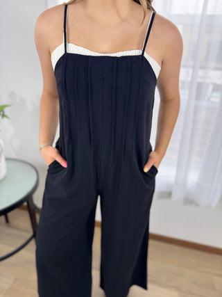 Person wearing a black jumpsuit with white trim in a room setting