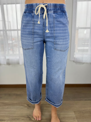 Blue jeans with a drawstring waist on a neutral background