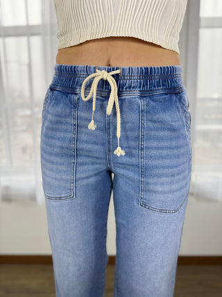 Light blue jeans with a drawstring waistband worn by a person indoors.