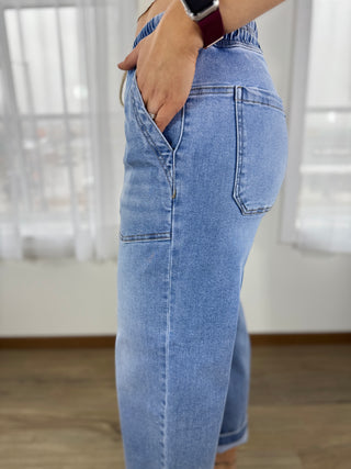 Person wearing light blue jeans with a blurred indoor background