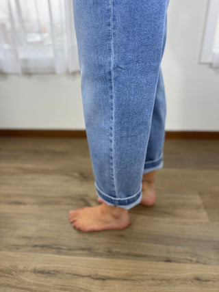 Person wearing blue jeans standing on a wooden floor.