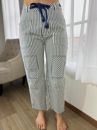 Person wearing blue and white striped pants with a tie in a room.