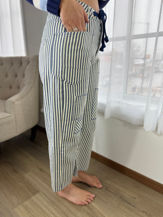 Person wearing striped pajama pants in a room with a couch and window.