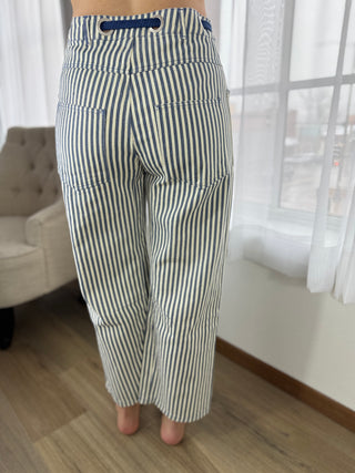 Striped pants worn by a person in a room with a chair and window.