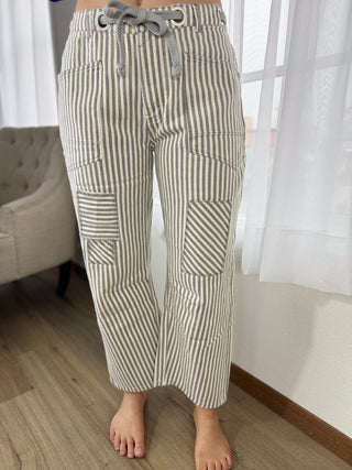 Striped pants worn by a person in a room with a couch and window.