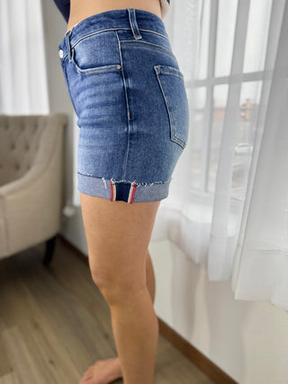 Person wearing a blue denim skirt in a room with white curtains.