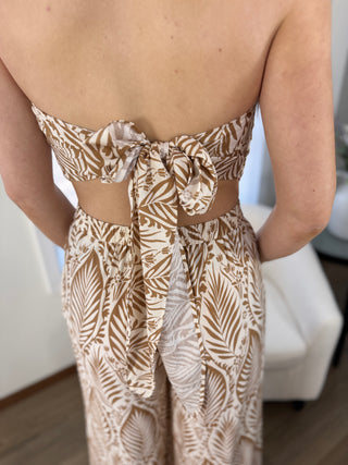 Person wearing a strapless top and high-waisted pants with leaf pattern indoors.