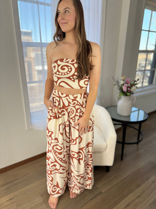 Woman wearing a strapless top and harem pants with a pattern in a room with large windows.