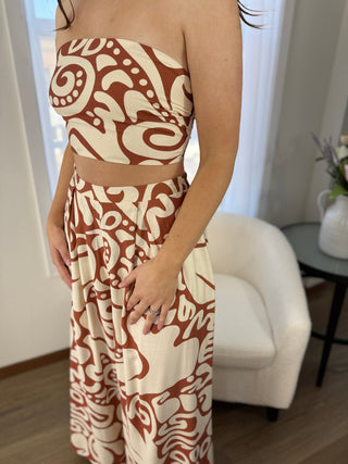 Person wearing a strapless dress with a brown and white pattern in a room.
