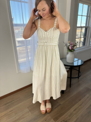 Woman wearing a striped dress in a room with large windows.