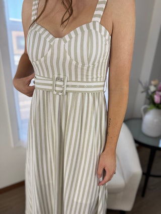 Woman wearing a white and green striped dress with a belt in an indoor setting.