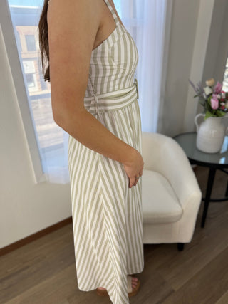 Woman wearing a striped dress in a room with a white chair and a window in the background.