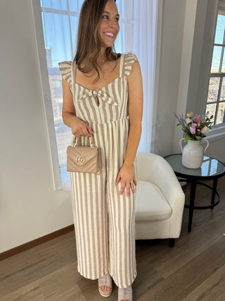 Woman in a striped dress holding a handbag in a room with large windows.