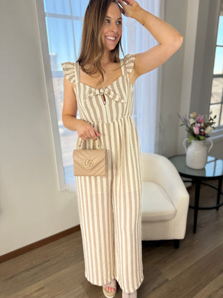 Woman in a striped dress holding a handbag in a room with a couch and flowers.