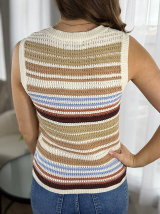 Woman wearing a sleeveless crochet top with horizontal stripes in various colors.